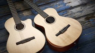 Two classical guitars laying side-by-side on a blue wooden floor